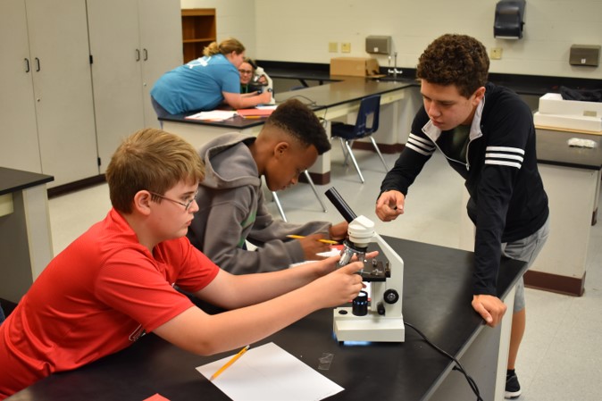 Students work with microscopes.