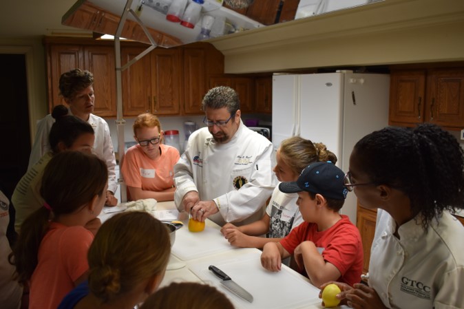 A chef teaches a class how to cut fruit.